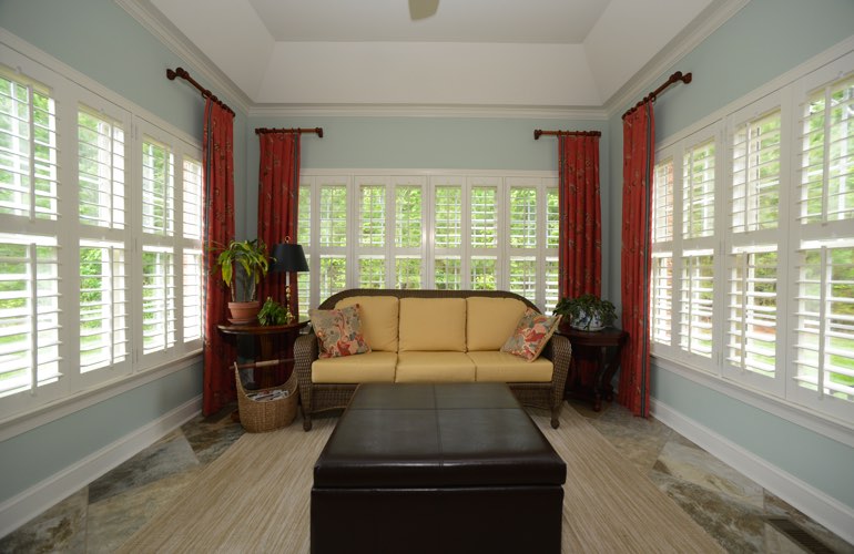 White plantation shutters covering windows in a sunroom